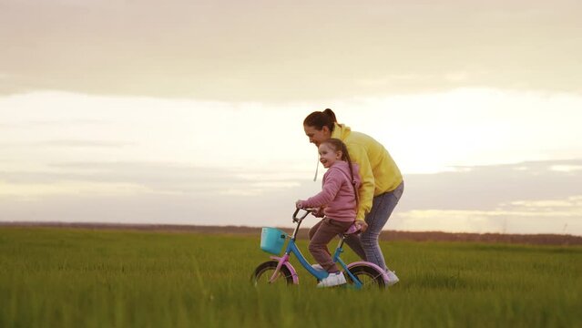 Little chilt learns ride bike field park sunset dot happy family concept. Child drives pedals two-wheeled bicycle evening walk. girl daughter rides bicycle green grass field park point children dream