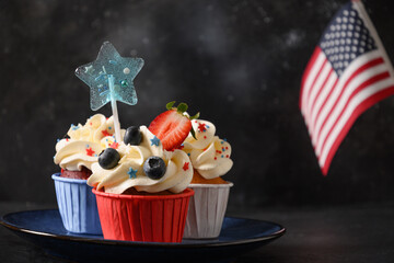 Traditional American vanilla three cupcakes with festive decorations and USA flag on black background. Food and dessert for Patriotic Independence Day 4th of july. Copy space.
