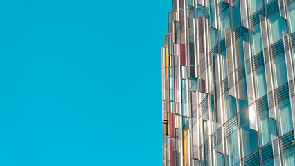 A modern skyscraper set against a blue sky - Powered by Adobe