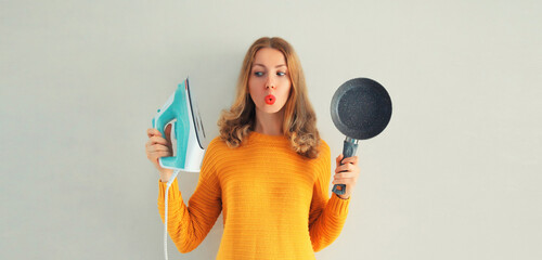 Household chores, choice of ironing or cooking - happy smiling woman housewife holding iron and...