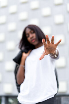 Black female youth fashion portrait with gray building background. Wearing a white t-shirt and black pants, lifestyle photos