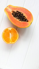 Papaya and orange tropical fruits on white wooden table