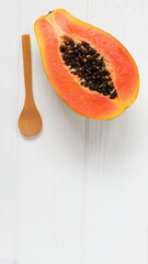 Papaya fruit and wooden spoon on white table