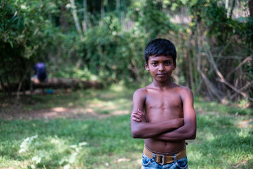 South asian shirtless young boy standing in nature looking confident, copy space for advertisement in left side 