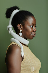 Side view of young black woman with white rat snake enlacing her hair bun standing in front of...