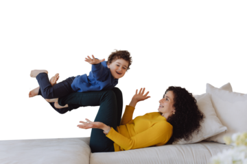 Boy likes to fly. Happy Italian mother older sister lying on back on sofa having fun with little kid lifting excited child boy in air against transparent background. Curly mom play airplane with son
