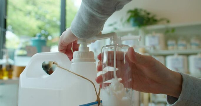 Man bring his own container buying eco bio organic goods in zero waste shop. male refilling natural biodegradable household product from container dispenser in plastic free grocery store. Hand Closeup