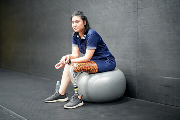 Portrait of disabled athlete woman with prosthetic leg in fitness gym
