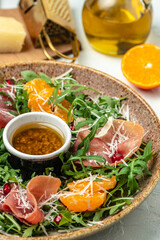 plate of arugula salad with mandarins, prosciutto jamon and Parmesan cheese. banner, menu, recipe place for text, top view