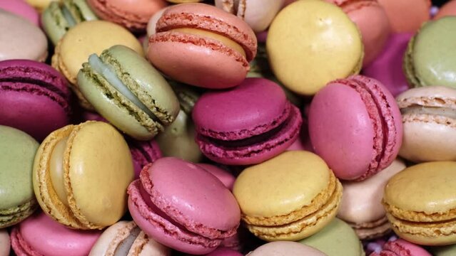 Top view of rotating fresh macaron cookies. Traditional french desserts from almond dough. Slow motion of colourful sweet macaron cakes spinning in a bakery shop. French cuisine or sweets concept.