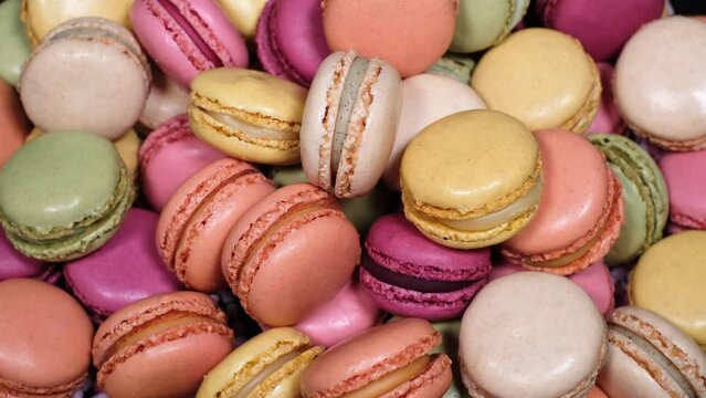 Top view of rotating fresh macaron cookies. Traditional french desserts from almond dough. Slow motion of colourful sweet macaron cakes spinning in a bakery shop. French cuisine or sweets concept.