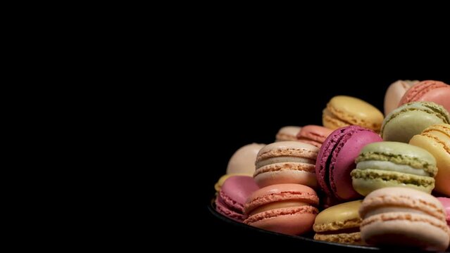 Close-up of rotating macaron cookies with copy space. Traditional french desserts from almond dough. Slow motion of colourful sweet cakes spinning in a bakery shop. French cuisine or sweets concept.