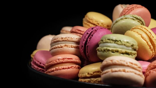 Close-up of rotating fresh macaron cookies. Traditional french desserts from almond dough. Slow motion of colourful sweet macaron cakes spinning in a bakery shop. French cuisine or sweets concept.