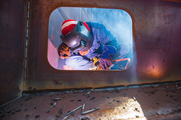 Male worker wearing protective clothing and repair pontoon manhole welding industrial construction...