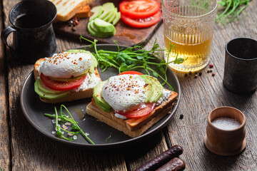 Fototapeta na wymiar Toast with poached egg, tomatoes and avocado. Healthy breakfast