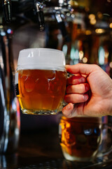 man bartender hand at beer tap pouring beer in glass in bar or pub