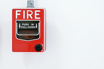 Manual pull fire alarm switch safety system box installed and fire extinguisher on white wall background.