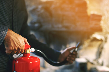 hand presses the trigger fire extinguisher available in fire emergencies conflagration damage background. Safety