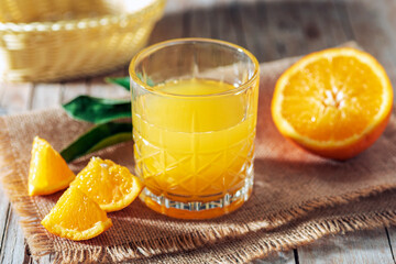 Obraz na płótnie Canvas Orange juice on sackcloth napkin on wooden table. Healthy drink. Closeup