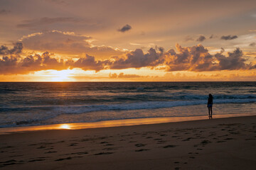 Fototapeta na wymiar Chinese woman on the beach against a spectacular ocean sunset in Phuket