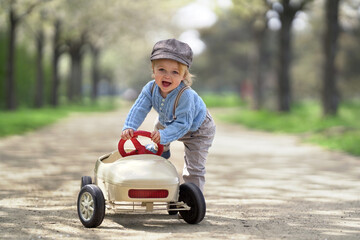 happy smiling boy is starting with his toy car