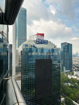 Building exterior of bank BRI with blue logo on top and reflection on glass windows.