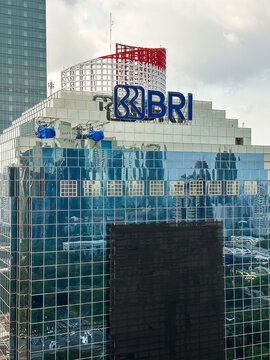 Building exterior of bank BRI with blue logo on top and reflection on glass windows.
