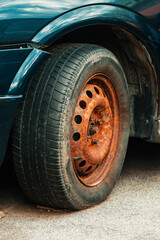 Fototapeta na wymiar Old rusty car wheel rim and worn tire