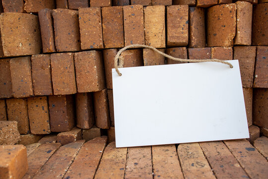 pile of stacked orange bricks with white hanging picture sign with empty free space for template or blank copy area 