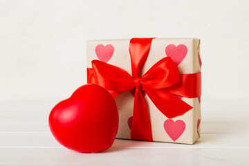 gift box with red bow and red heart on colored background. Perspective view. Flat lay