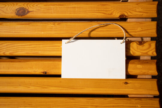 white hanging picture sign on golden wooden chair slats with empty free space for template or blank copy area