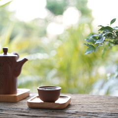 traditional tea pot and tea cup on wooden table outdoor greenery view