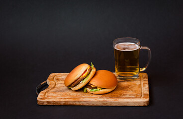 Mug of beer and burgers on cutting board. View with copy space.