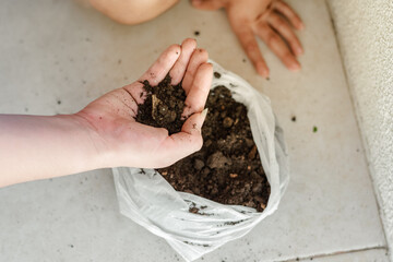 detail of a woman's hand grabbing earth from the sack to start planting