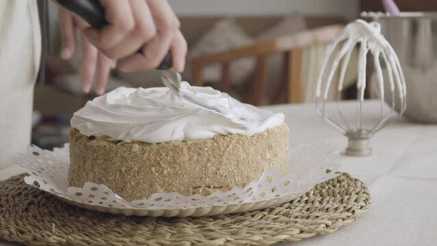 confectioner's hand finalizing meringue on a sheet cake with a spatula
