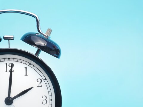 Close up of Black retro alarm clock at 2am 2pm on a blue background with copy space to add text