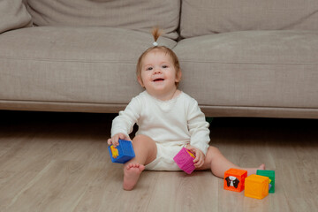 baby girl sitting at home on the floor playing cubes, child development