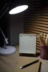 Desktop calendar, lamp, and pencil placed on student wooden desk at night. calender for planner to plan daily appointments each day, month, and year on wooden table. Calendar background concept.