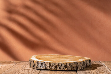  Slice wooden podium round saw cut of a tree on a brown background. Still life for the presentation of products. palm shadows. Copy space. © Yevhenii Khil