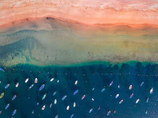 Aerial top down view of Playa de Las Teresitas during golden hour with beautiful sand beach and shallow clear water with colorful boats on Tenerife, Spain