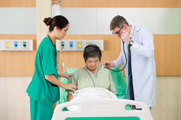 Obraz premium senior woman patient lying in hospital bed and doctor team working at hospital ward. Healthcare medical and medicine concept.