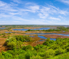 Obraz premium view fhom green hill to the blue river among prairie under blue cloudy sky