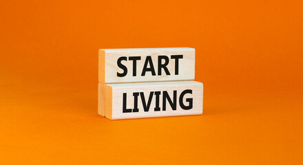 Start living symbol. Concept words Start living on beautiful wooden block. Beautiful orange table orange background. Business and Start living concept. Copy space.
