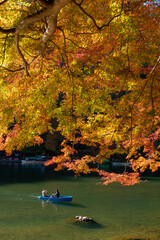 Visitors take in the colors of autumn along the Hozu-gawa River in Kyoto while riding a wooden boat at Japan