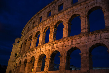 Fototapeta premium Beautiful Pula Arena at Night. European Historical Landmark with Evening Sky. Roman Amphitheater with Arch in Istria.