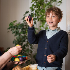 Happy boy holding a broken painted Easter egg. The traditional duel game of who has harder egg.