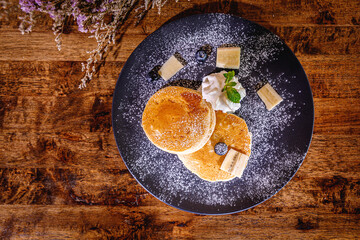 A stack of banana pancakes with slices of fresh bananas, walnuts and honey on top with cup of tea on a wooden background. A healthy breakfast. Copy space