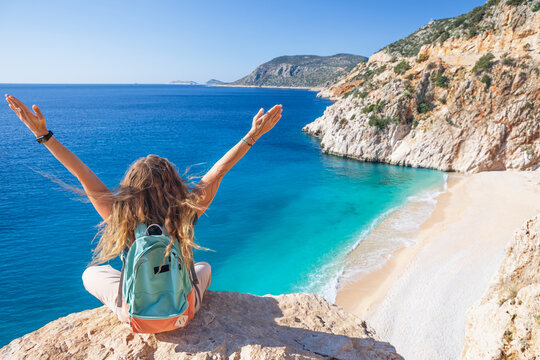 Young woman with backpack looking out over Kaputas beach, Lycia coast. Summer day walk by Lycian way at family vacation in Mediterranean Sea, Kas, Antalya region, Turkey