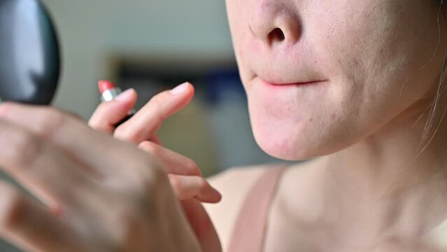 Cropped shot of woman while applying lipstick on her lips. Lipstick is makeup that makes your lips look darker, redder, or shinier.