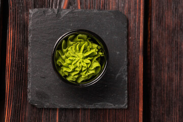 Green wasabi sauce or paste in bowl on wooden background top view